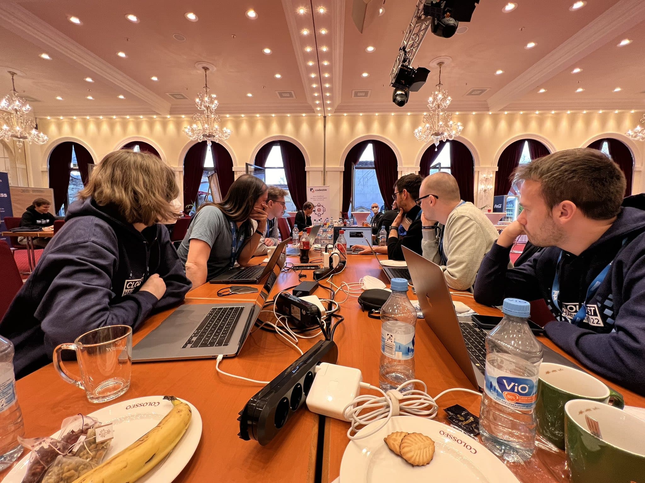 a collection of people sitting at a table with laptopls in front of them